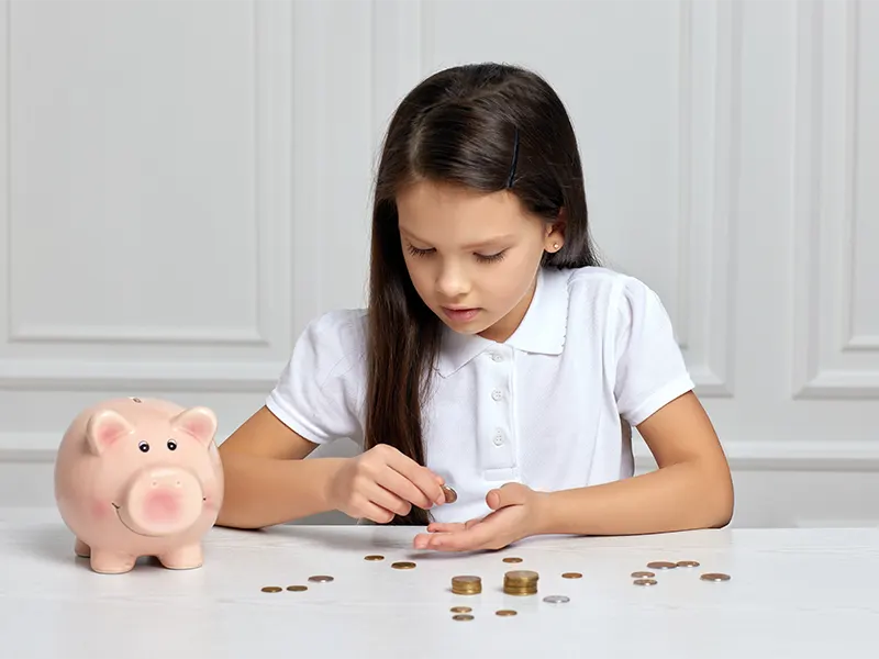 Money literacy for girls in the USA and India, depicted through textbooks and a shopping cart filled with dollar bills.,How Families Can Support Financial Literacy,How to Teach Financial Literacy to Girls,Challenges Girls Face in Financial Literacy,Why Money Literacy Matters for Girls,Money Literacy for Girls and Maidy in the USA and India