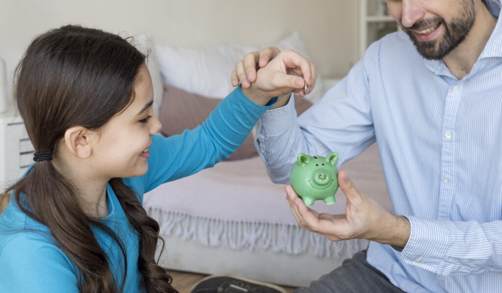 3 Surprising Ways Family Conversations Shaping Toddler Money Habits: The Early Financial Foundation 2 father daughter putting money piggy bank Family conversations shaping toddler money habits,
Toddler financial language development India,
Early money habit formation through talk,
Parent financial talk influence on children,
Conversational financial literacy for toddlers